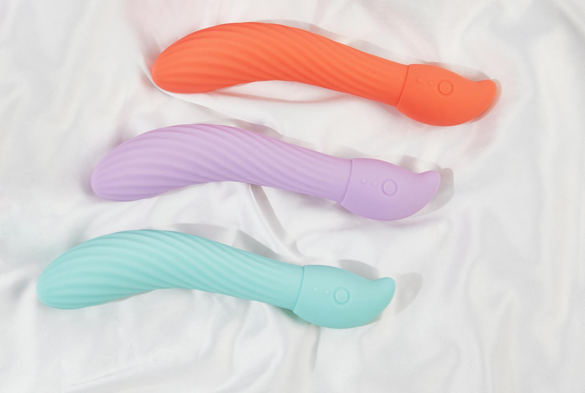 Collezione di vibratori colorati su sfondo giallo brillante, mostrando varie forme e design