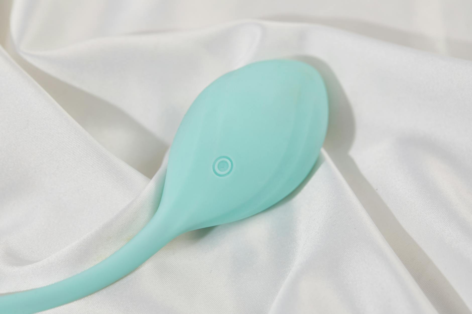 Un vibratore di colore teal su tessuto di seta bianca liscia, perfetto per l'immagine di uno stile di vita per adulti