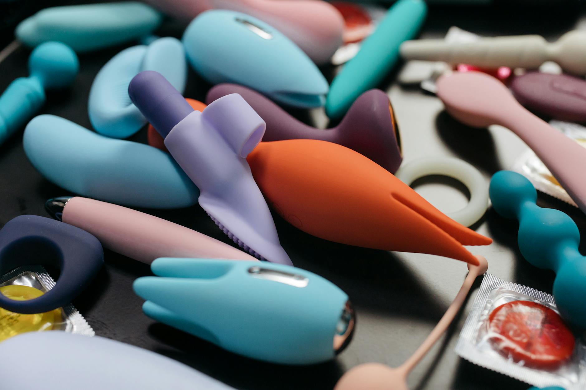 A hand holding an orange vibrator against a minimalistic purple backdrop