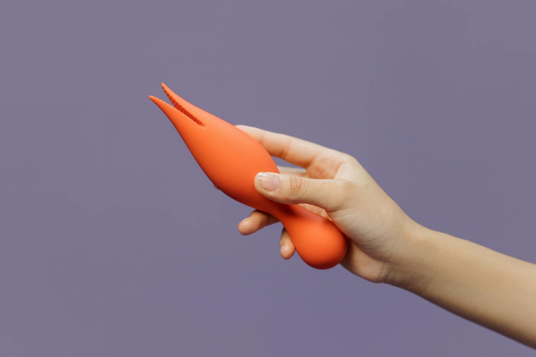 Un primo piano di una mano che tiene un vibratore colorato su uno sfondo minimale, mostrando sensualità moderna