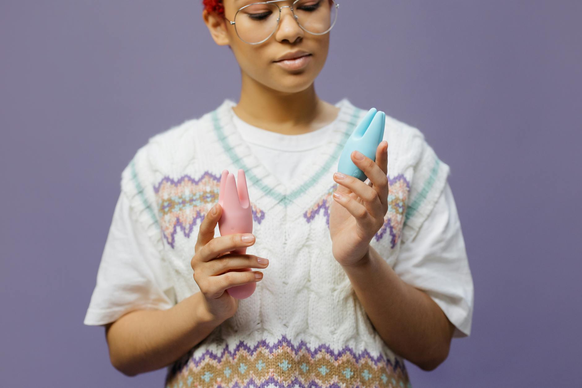 Close-up of hands holding a sleek blue lemon vibrator against a purple background