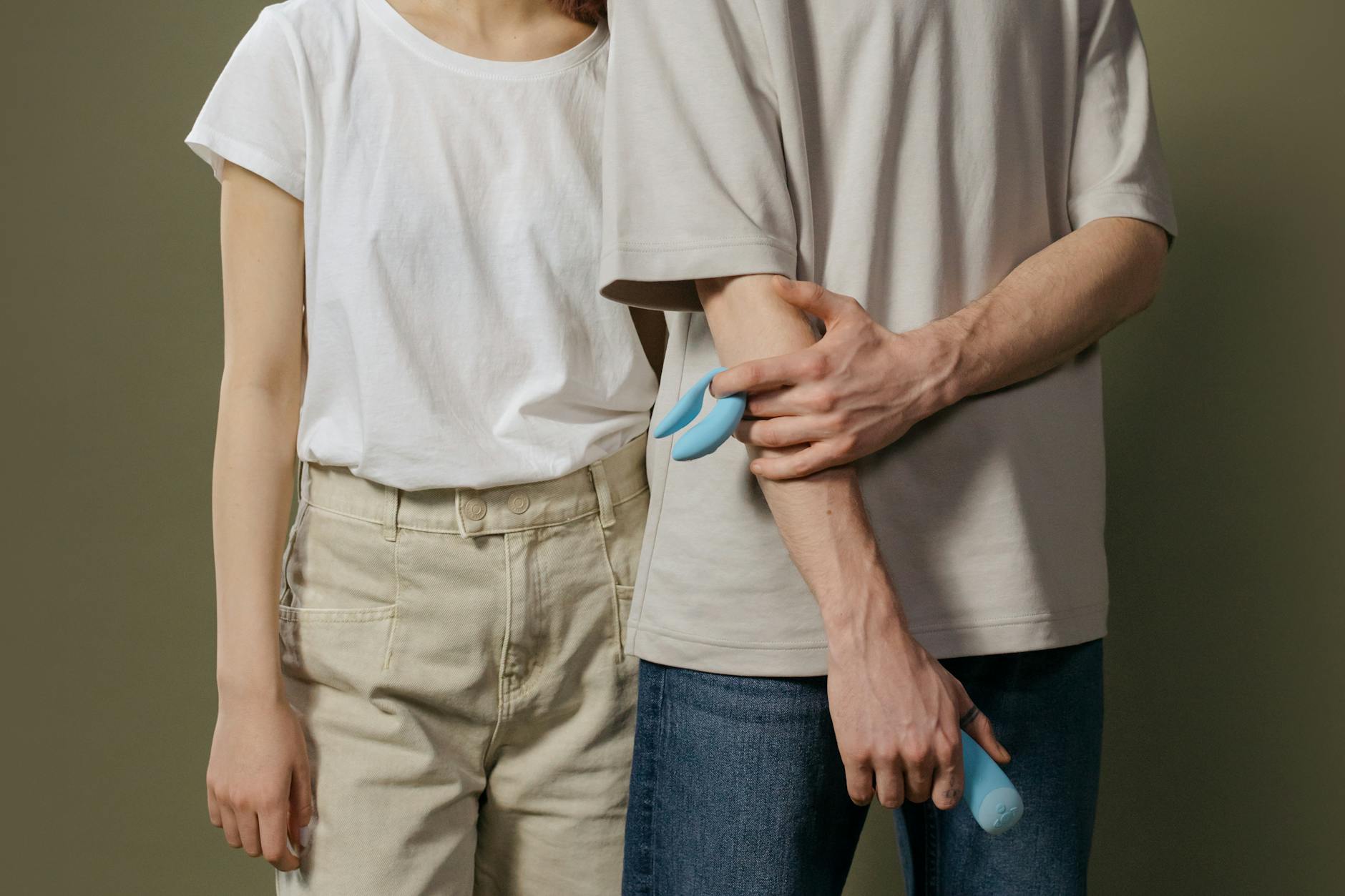 Close-up of hands holding a sleek blue vibrator against a purple background